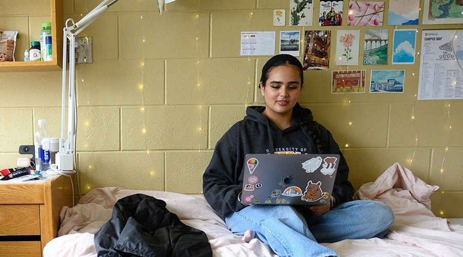Student sitting on a bed in a University of Waterloo residence