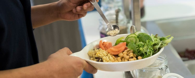 Studnet filling a bowl with food