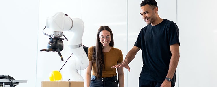 Two students observing a robot