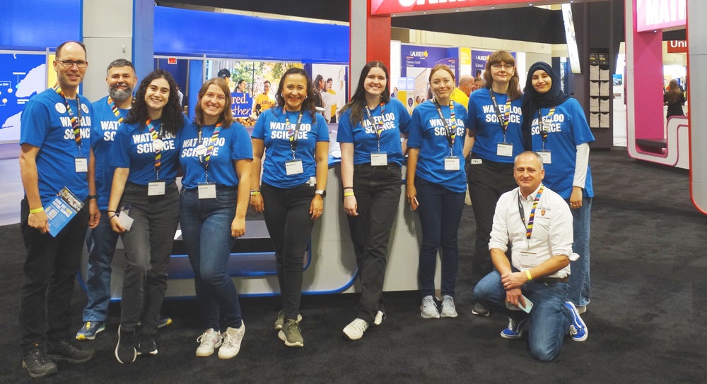 Students in blue shirts stand in a line at the Ontario Universities' Fair