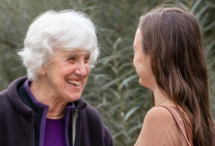 Katie and her grandmother smile at each other outside