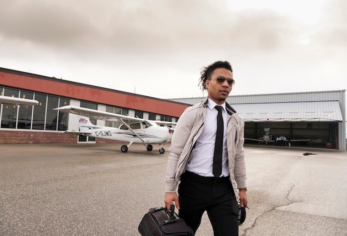 A person wearing a suit walking away from a plane.