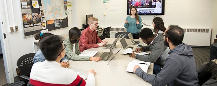 group of students in active discussion around a classroom table