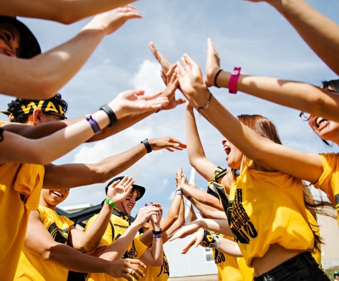 A group of students cheering with their arms in the air