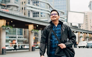 Student in black jacket walking in urban setting