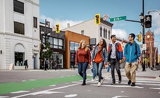 Students walk along a city street on a sunny day