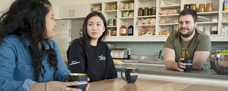 three students talking at a table at an eatery