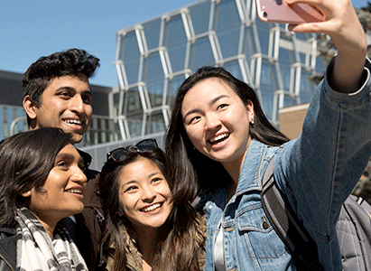 Students taking a selfie with a glass walled building behind