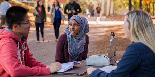 Students sitting outside at table in the autumn