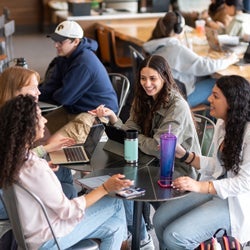 4 students sitting at round table in a coffee shop