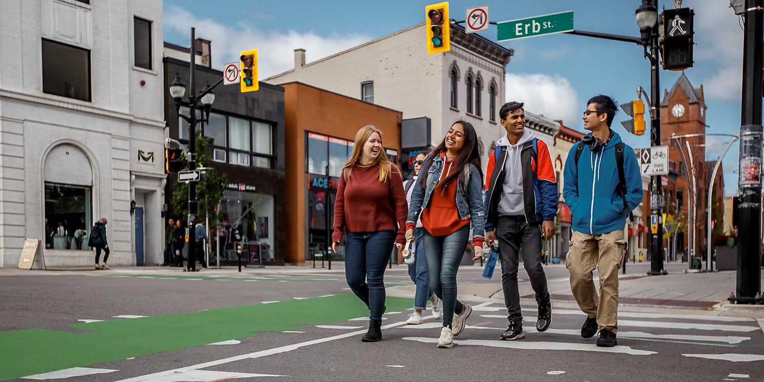 Four students walk across a street in Uptown Waterloo
