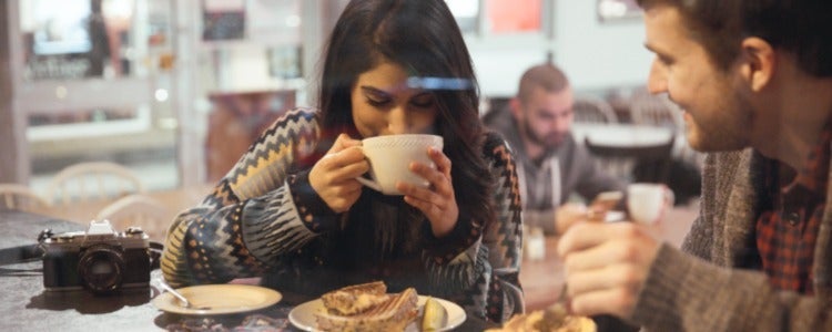 Two students eat dinner together in front of the glass window in the storefront of an Uptown Waterloo restuarant