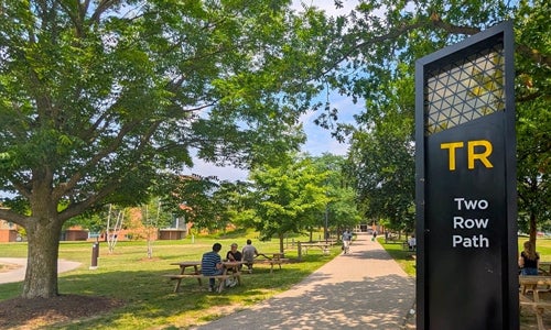 Two Row Path with trees on either side and students sitting at a table