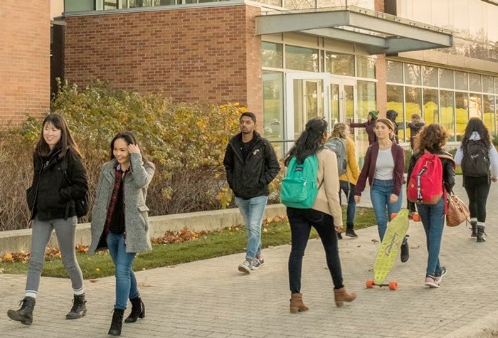Students walking by brick and glass building
