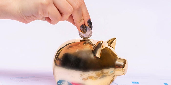 Hand putting a coin in a piggy bank