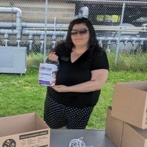 Vanessa stands behind a table with food bank boxes