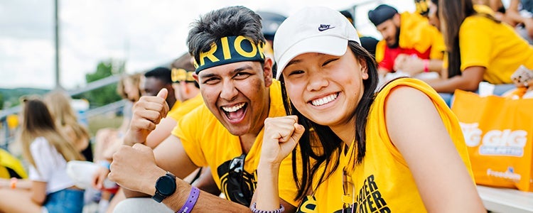 Two students cheering and smiling for a photo