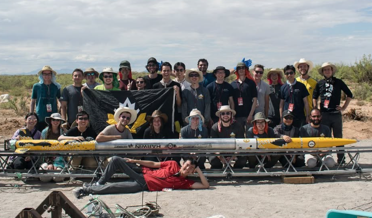 Engineering students gather behind a large rocket
