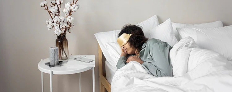 Girl sleeping in bed with and eye mask on.