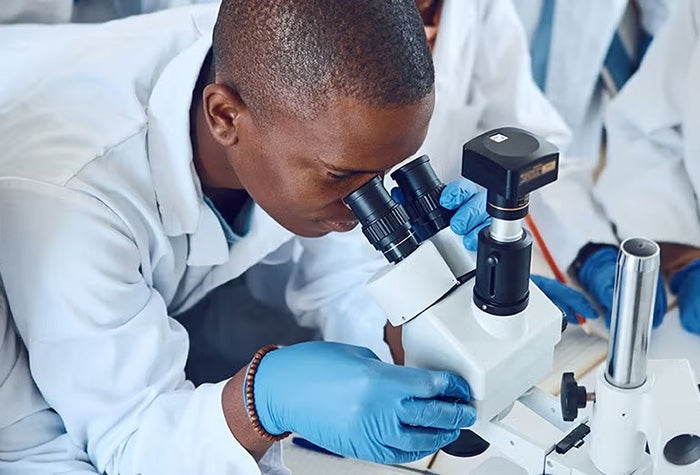 Person in a lab looking through a microscope.