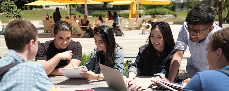 Group of students studying outside on a bench in the Arts Quad