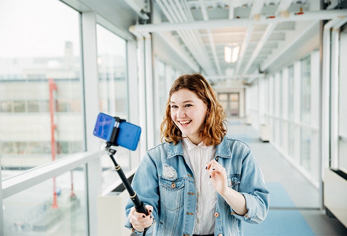 Student recording herself with her phone attached to a selfie stick