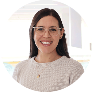 Clare has brown hair and glasses and smiles widely.