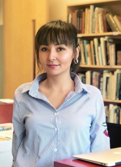 Dr. Aynur Kadir standing in front of a bookshelf