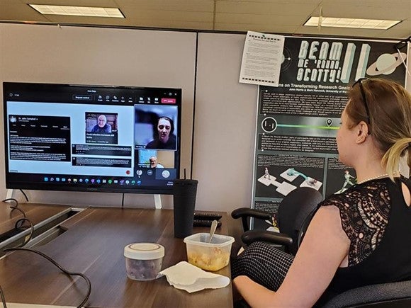 A GI Staff member watching Heeg's talk on a large screen while eating lunch