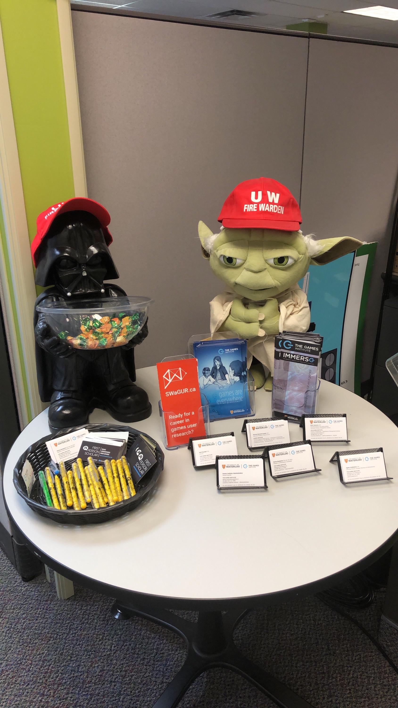 Darth Vader and Yoda sitting on welcome desk with pens and business cards