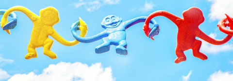 plastic monkeys linking hands in a chain, (right to left) red, blue, yellow