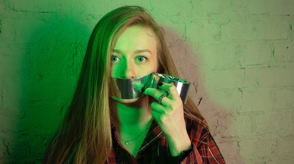 girl with duct tape covering her mouth so she cannot speak