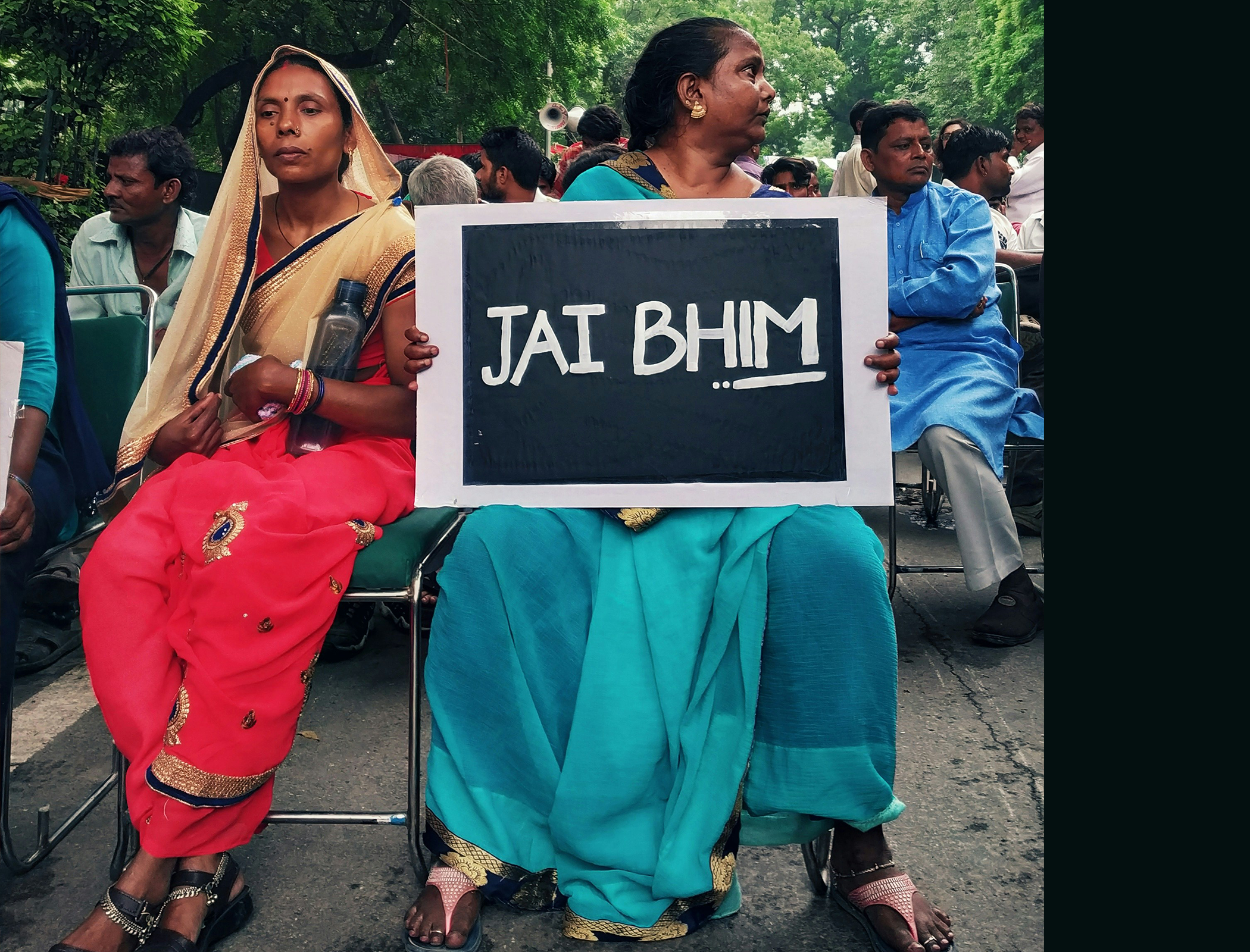 Two women at a rally with a sign in Hindi " Jai Bhim" which means hail Bhim.