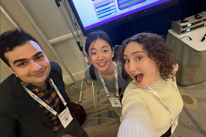 taylor in front of poster at conference with friends 