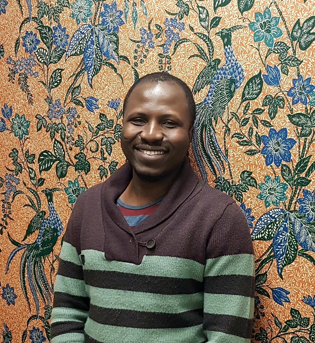 George Atiim standing in front of a colourful wall
