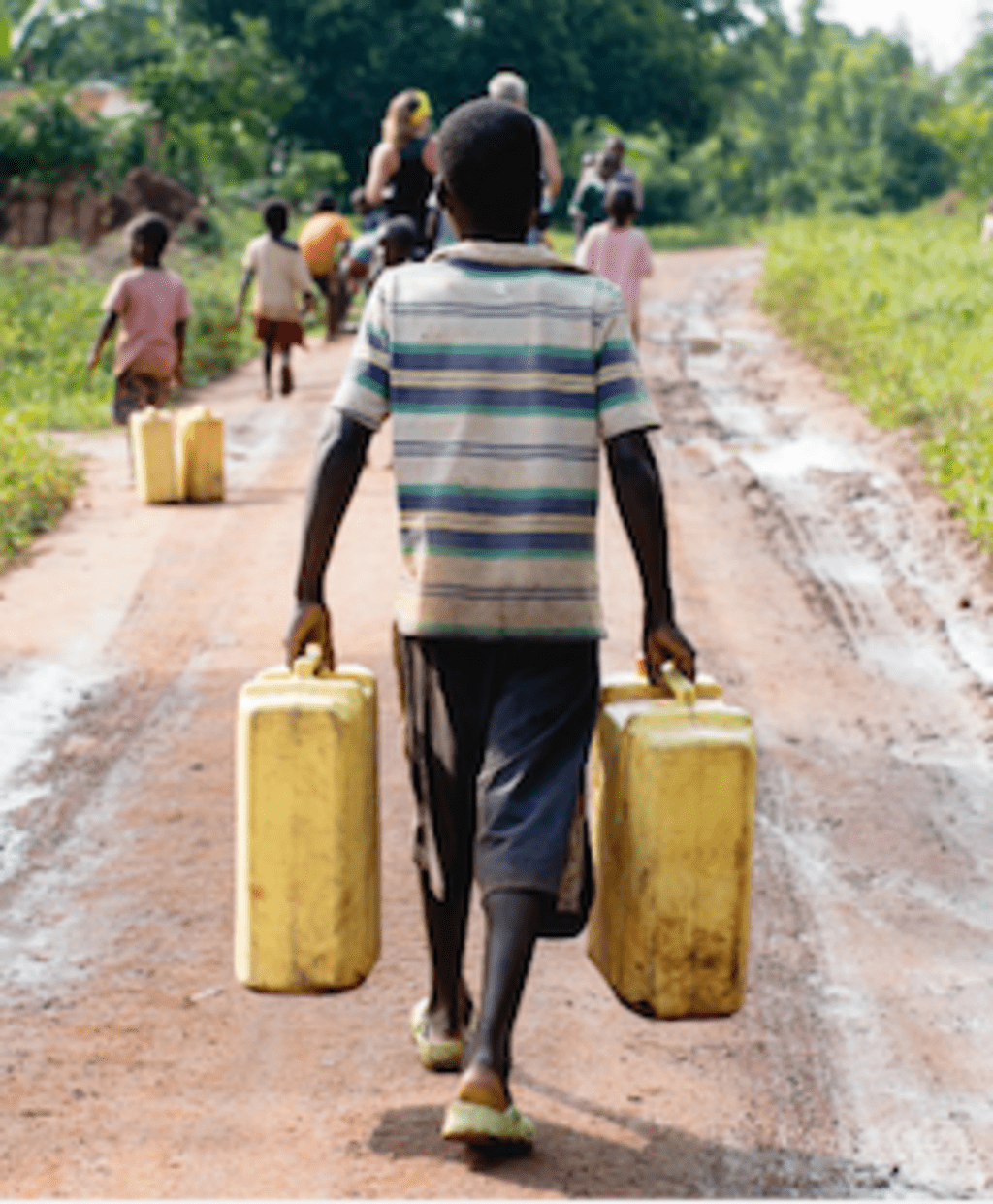 Young Ugandan boy carrying water jugs along dirt pathway