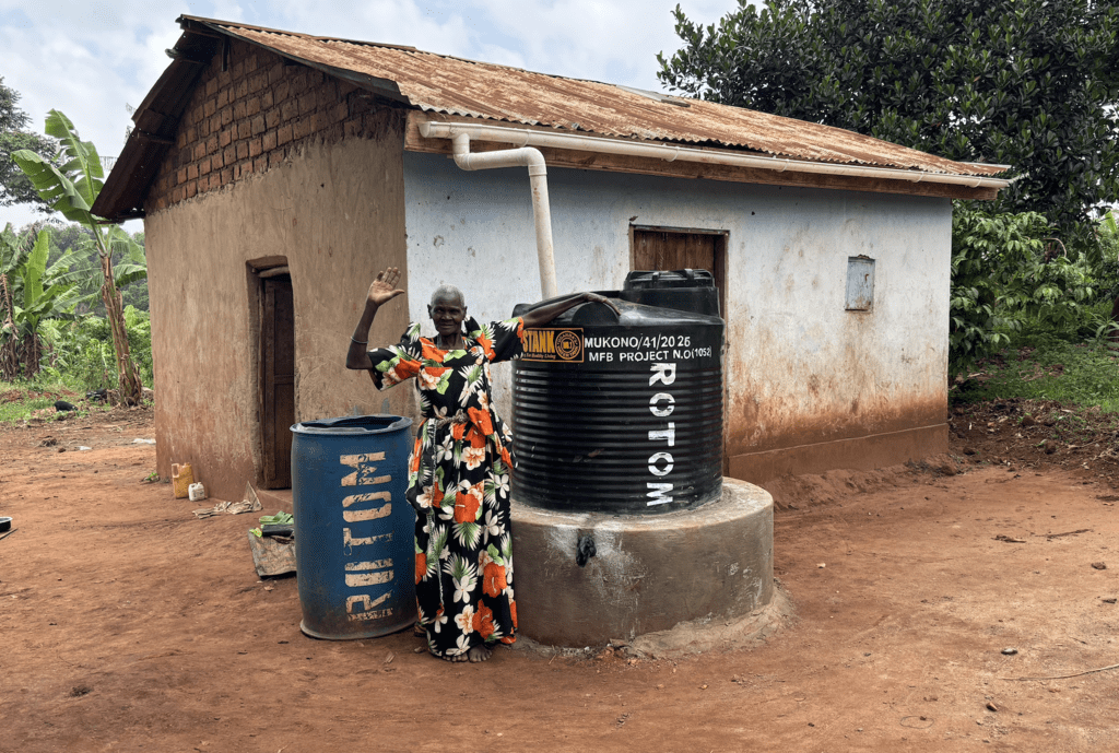 older woman standing next to rotom water tank