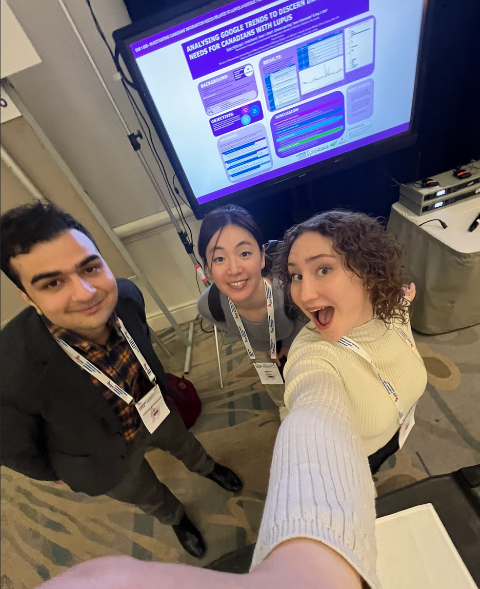 taylor in front of poster at conference with friends 