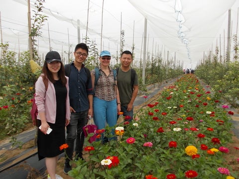 Steffanie Scott and students by flowers in a greenhouse