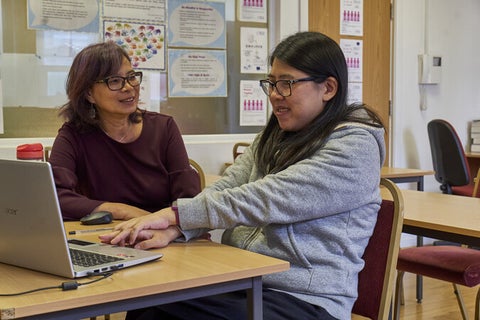 Two women sitting at desk with a computer