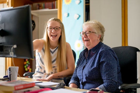 Two women sitting at desk with a computer