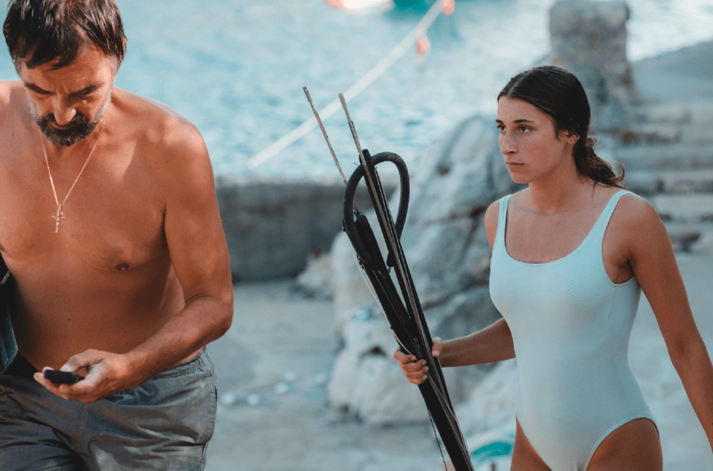 A man and a woman in bathing suits. The woman holds a diving gun. 