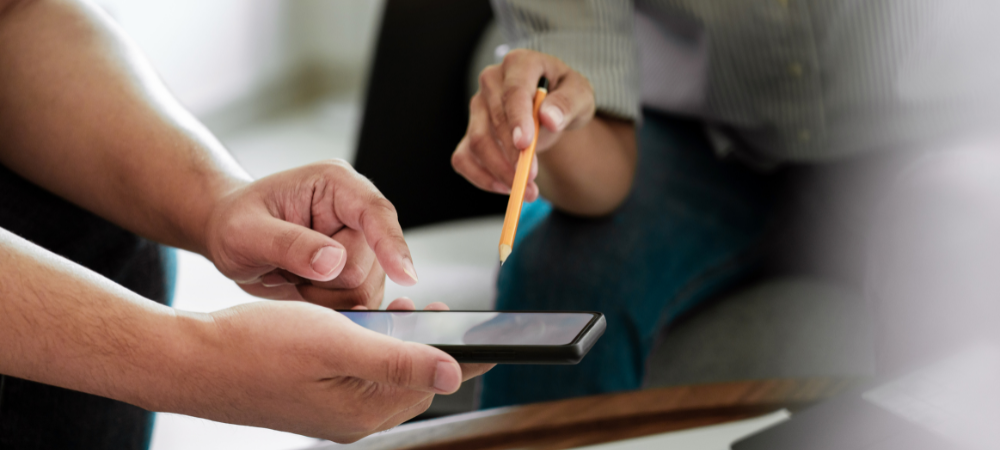 Two people gesturing to a mobile phone