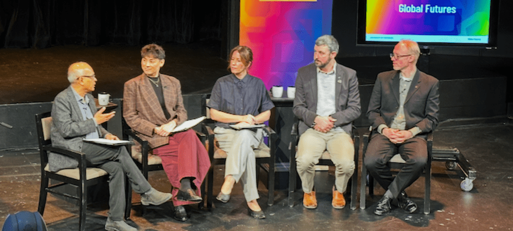 five people seated on a stage in conversation