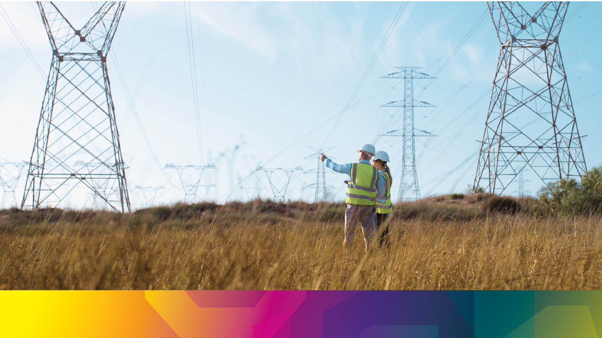 Two people among energy transmission towers seen from a distance 