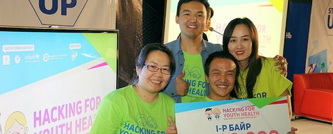 Four smiling students holding Hacking for Youth Health sign.