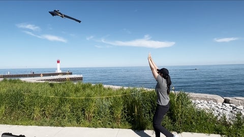 A researcher launching a monitoring drone into the air.