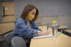 Female student in yellow mask at a desk in lecture hall