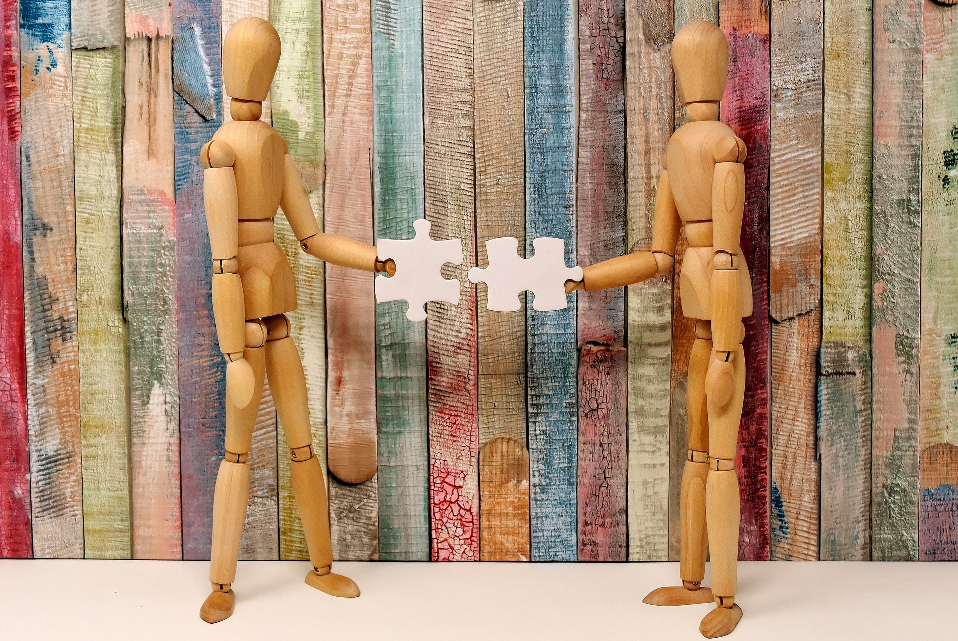 two wooden figures fitting puzzle pieces together