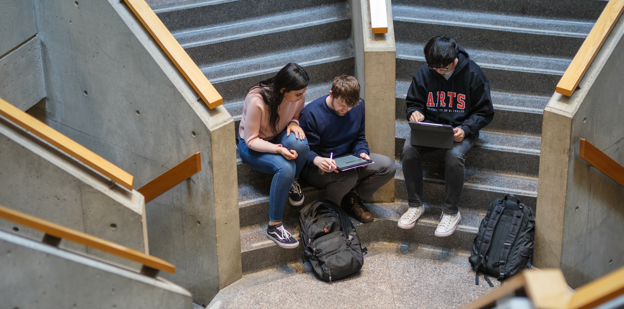 Students reading books while sitting on a staircase.